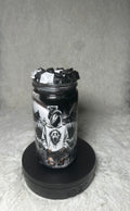 A clear glass jar filled with black wax and topped with black wax flakes, featuring a detailed black and white graphic of a screaming face character, displayed on a black circular base against a gray textured background.